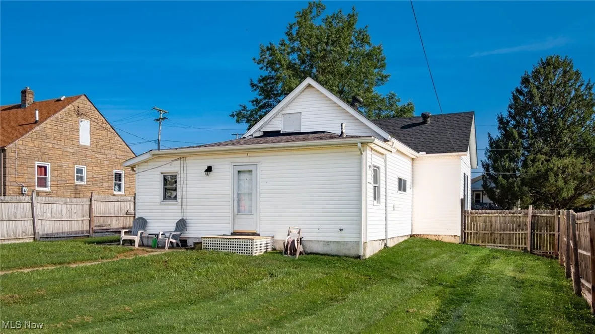 Back of property featuring a fenced backyard and a shingled roof