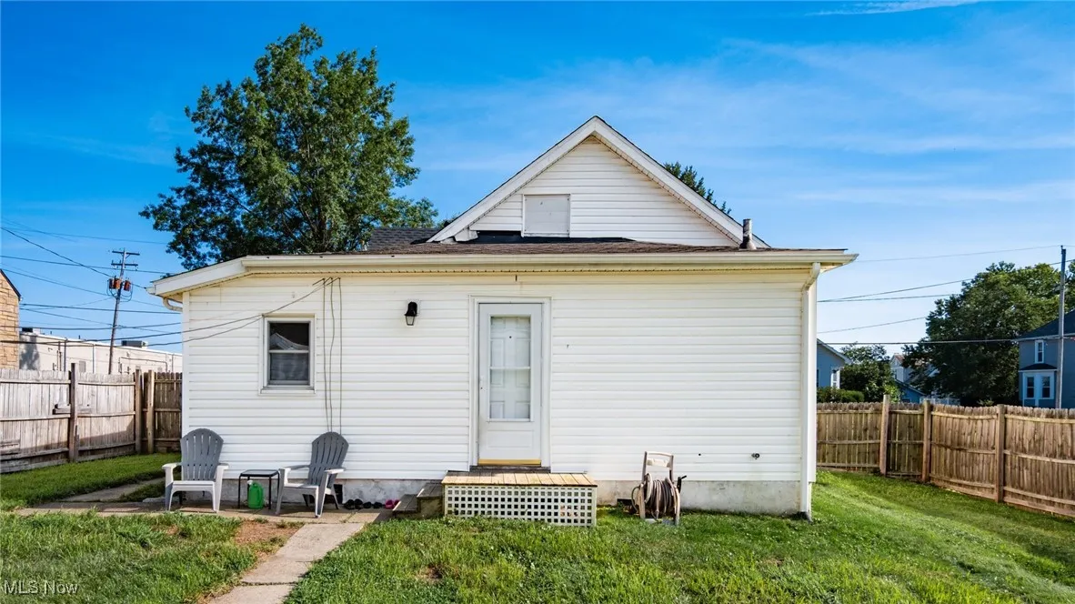 Rear view of house with a fenced backyard and roof with shingles