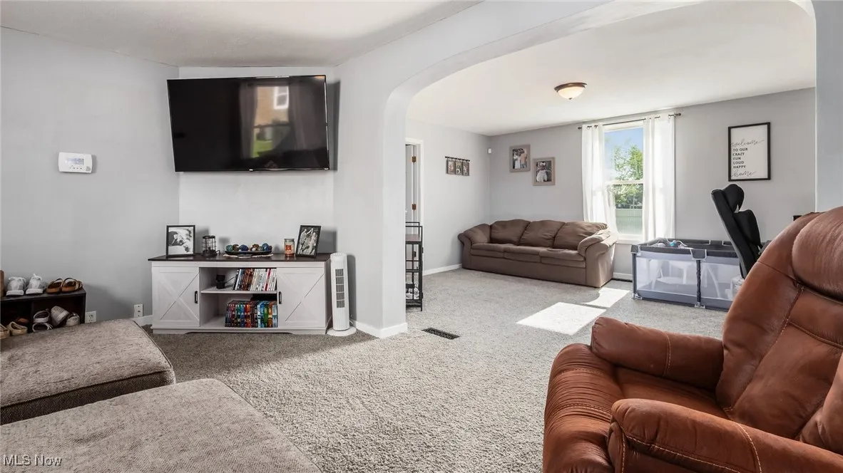 Carpeted living area featuring arched walkways and baseboards