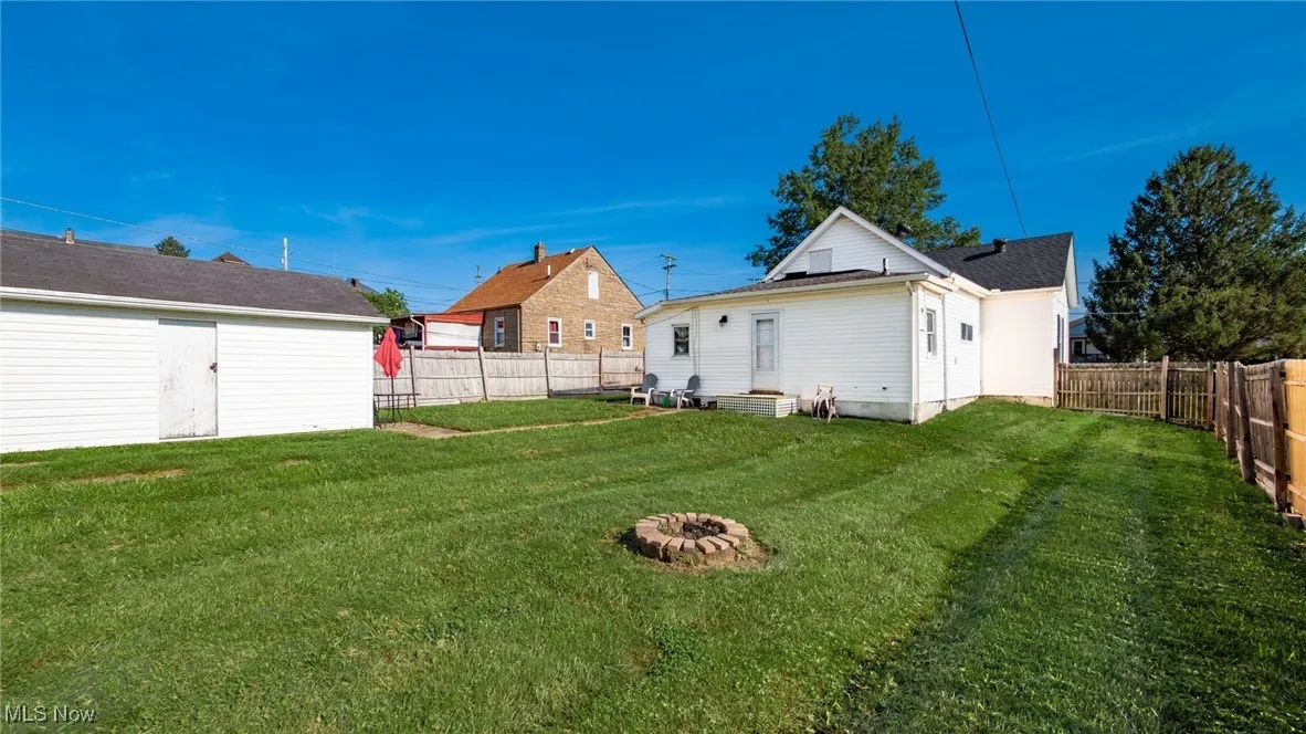 Fenced backyard with an outdoor fire pit and entry steps