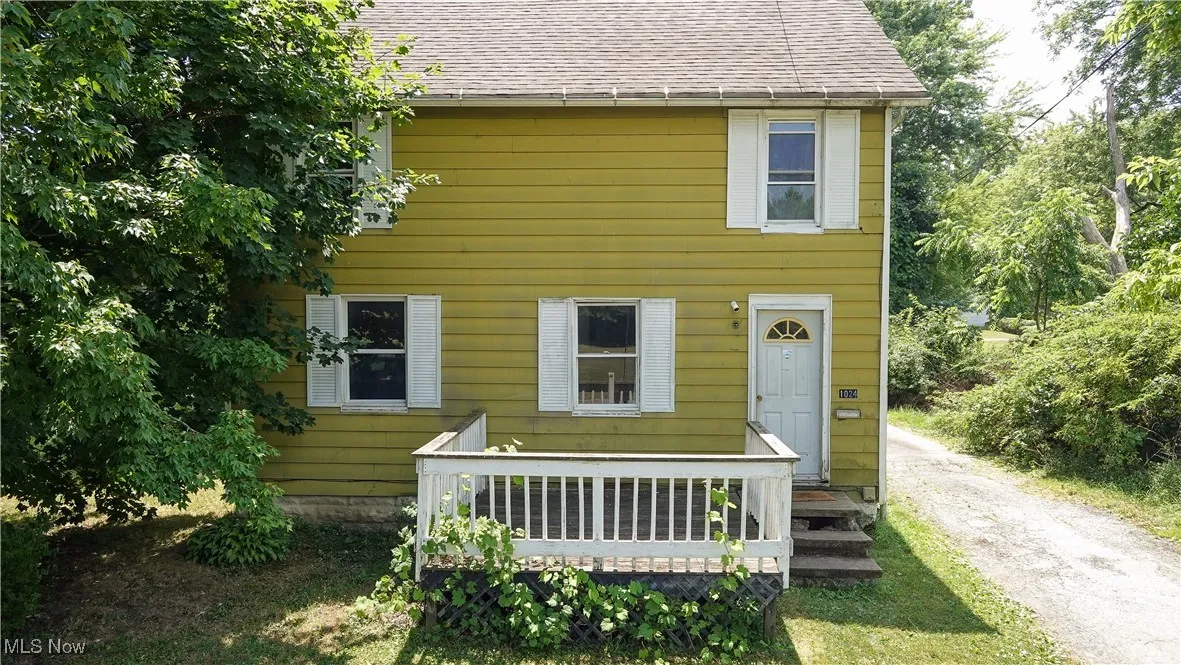 Rear view of property with a shingled roof and driveway