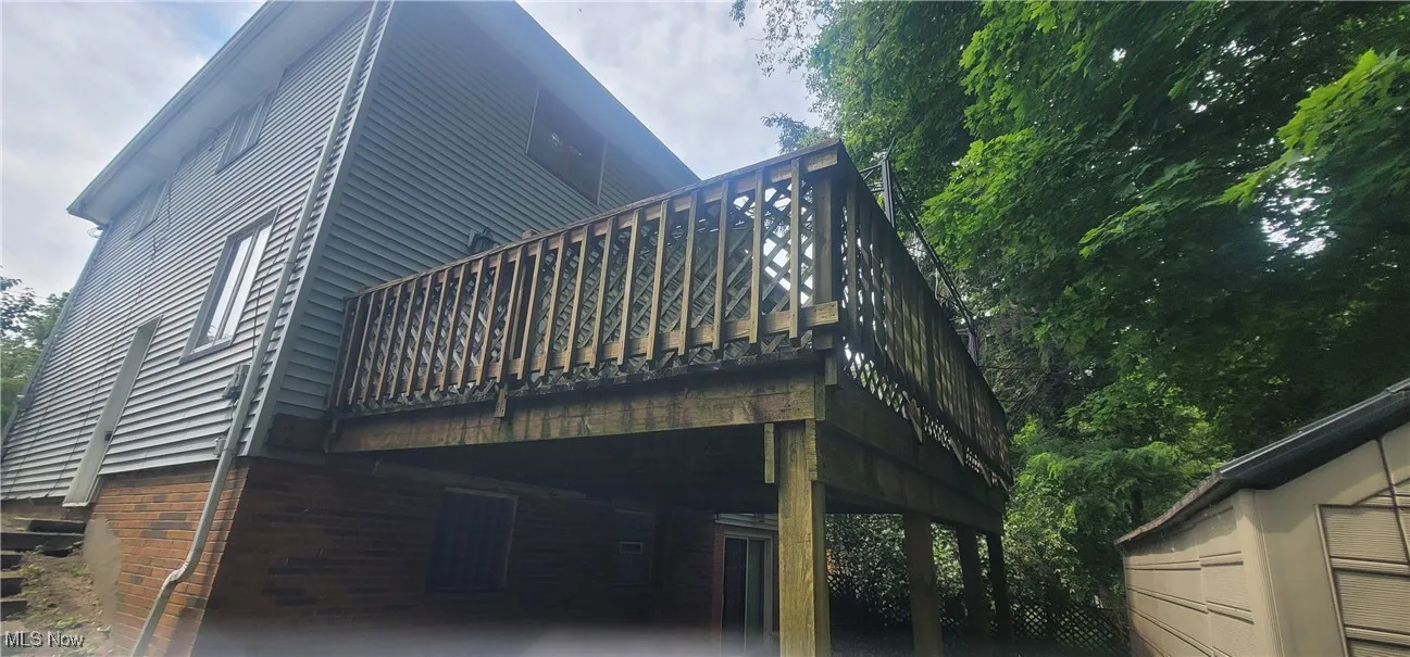 Rear view of property with stairway, a carport, and a wooden deck