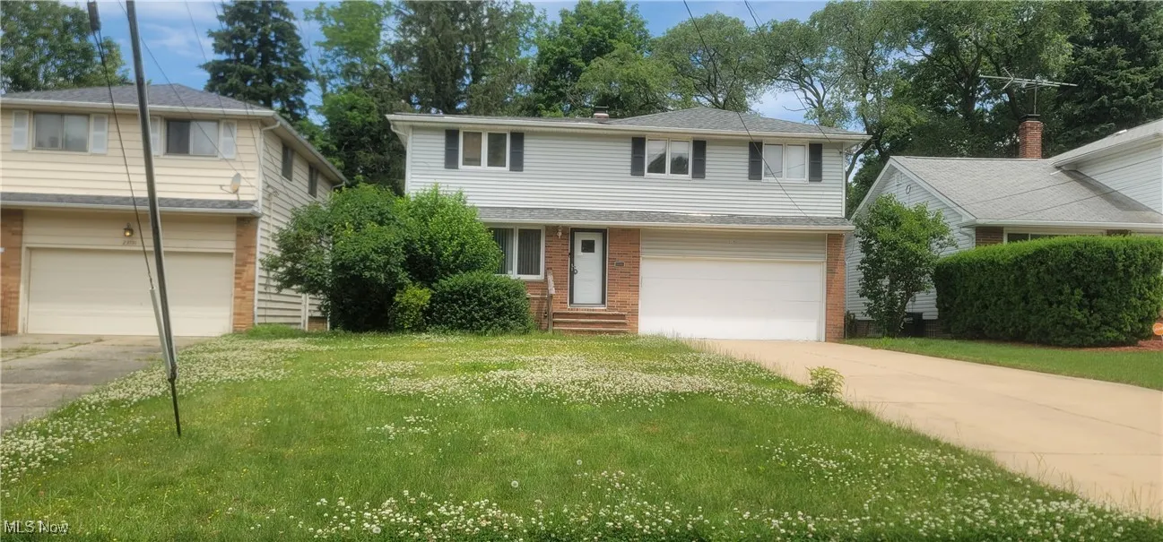 Traditional-style home featuring concrete driveway, a garage, brick siding, and a front yard