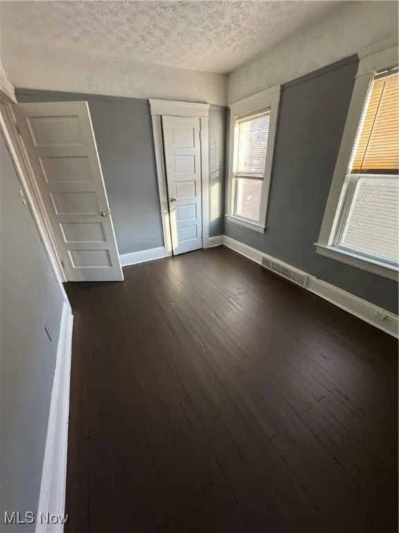 Unfurnished bedroom featuring a textured ceiling and dark wood-style floors