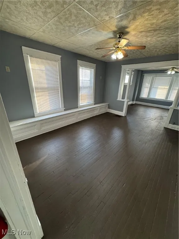 Unfurnished room featuring a ceiling fan and dark wood finished floors