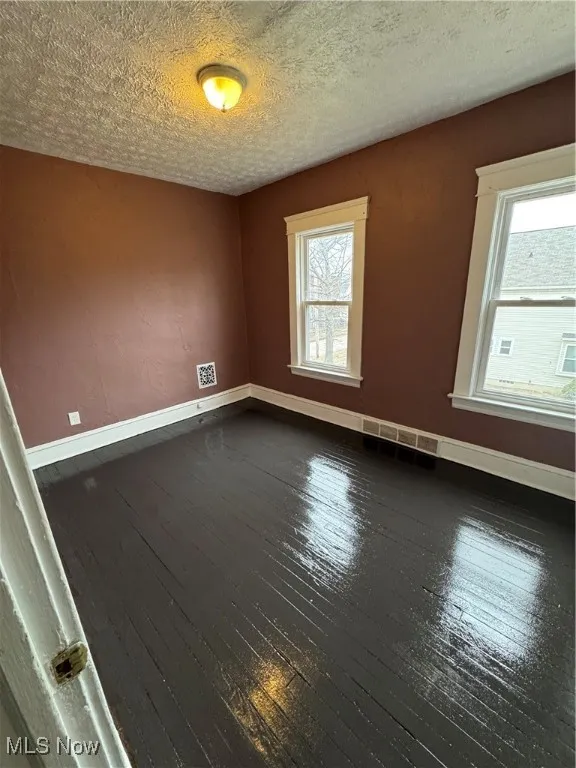 Spare room featuring dark wood finished floors and a textured ceiling