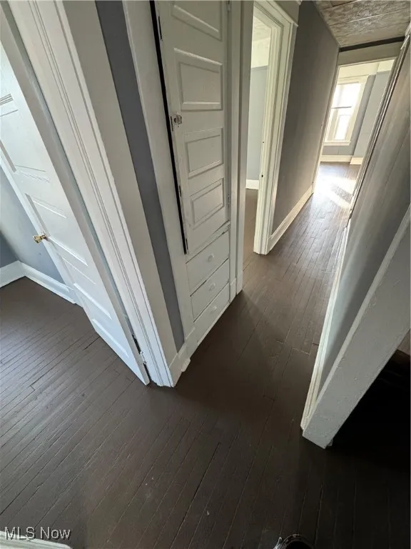 Corridor featuring dark wood-type flooring and baseboards