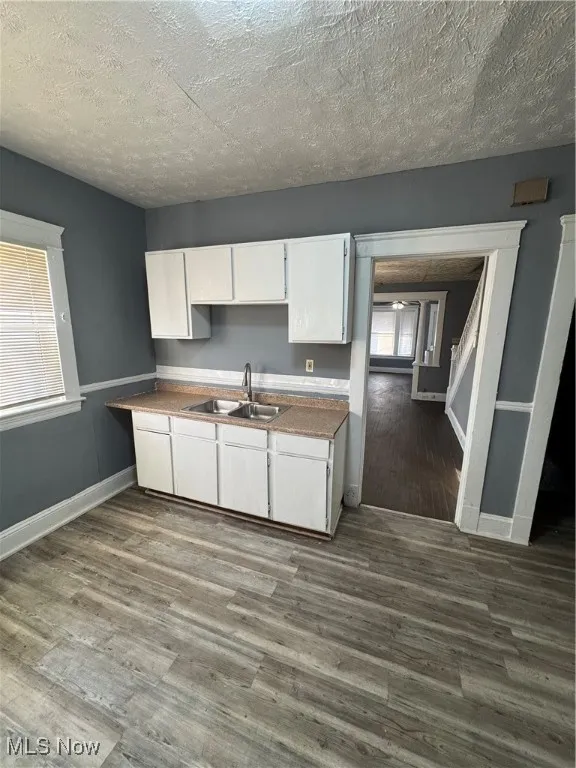Kitchen featuring white cabinets, a textured ceiling, and dark wood-style flooring