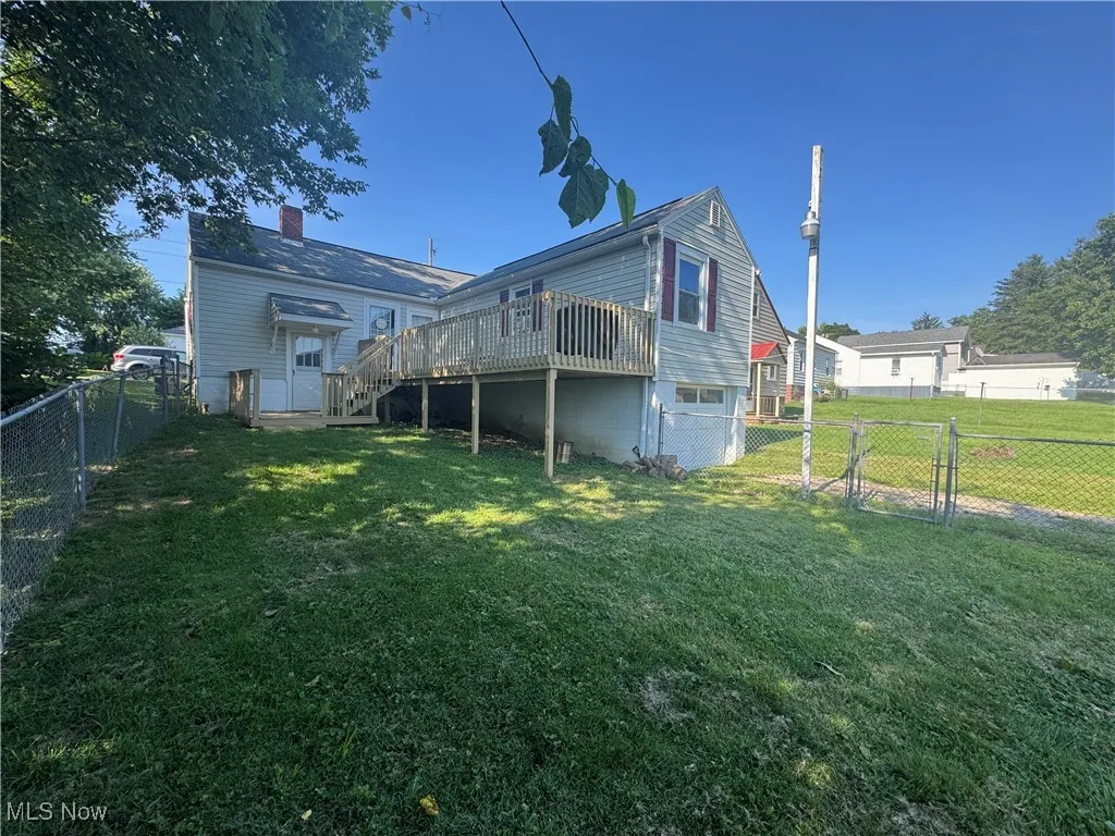 Back of house featuring a wooden deck, a fenced backyard, stairs, and a chimney