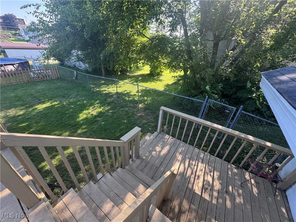 Wooden terrace with a fenced backyard