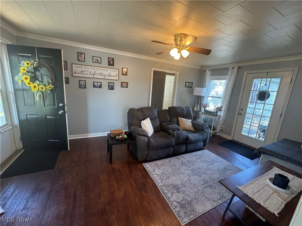 Living area featuring wood finished floors, crown molding, and a ceiling fan