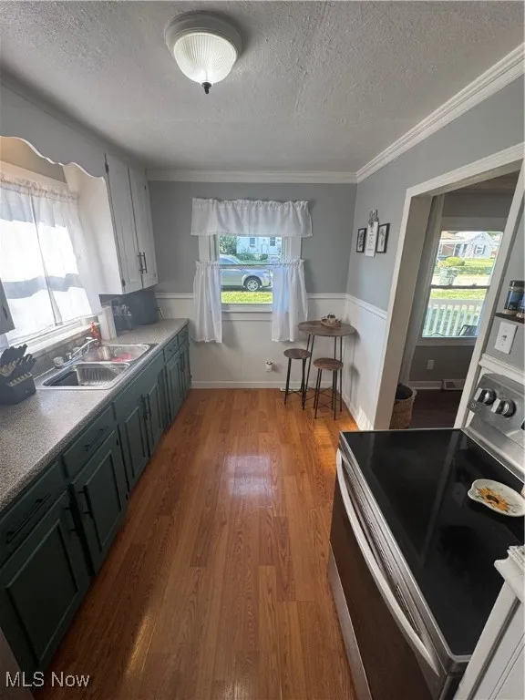 Kitchen featuring range, a textured ceiling, crown molding, plenty of natural light, and wainscoting