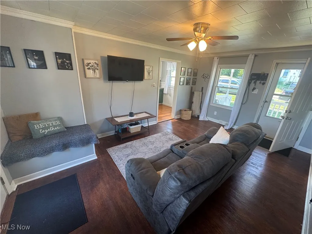 Living area with ornamental molding, wood finished floors, and a ceiling fan
