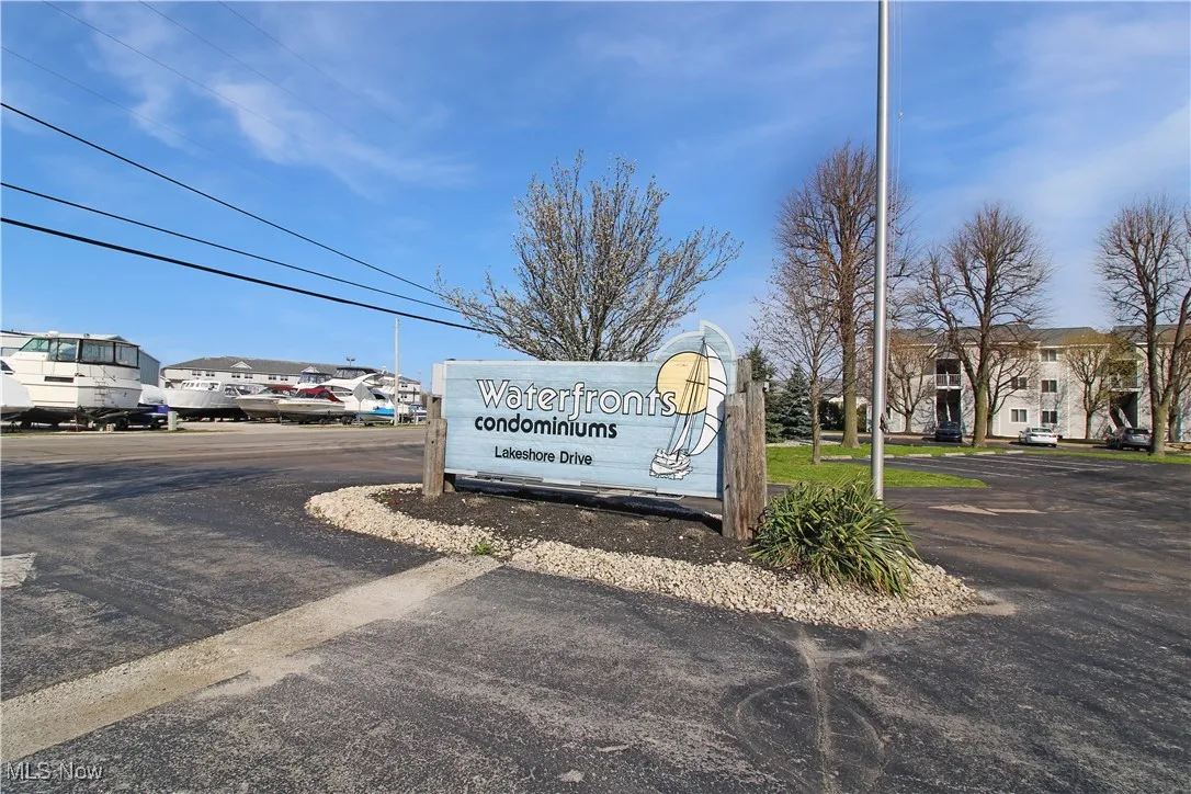 Community sign with uncovered parking and a residential view