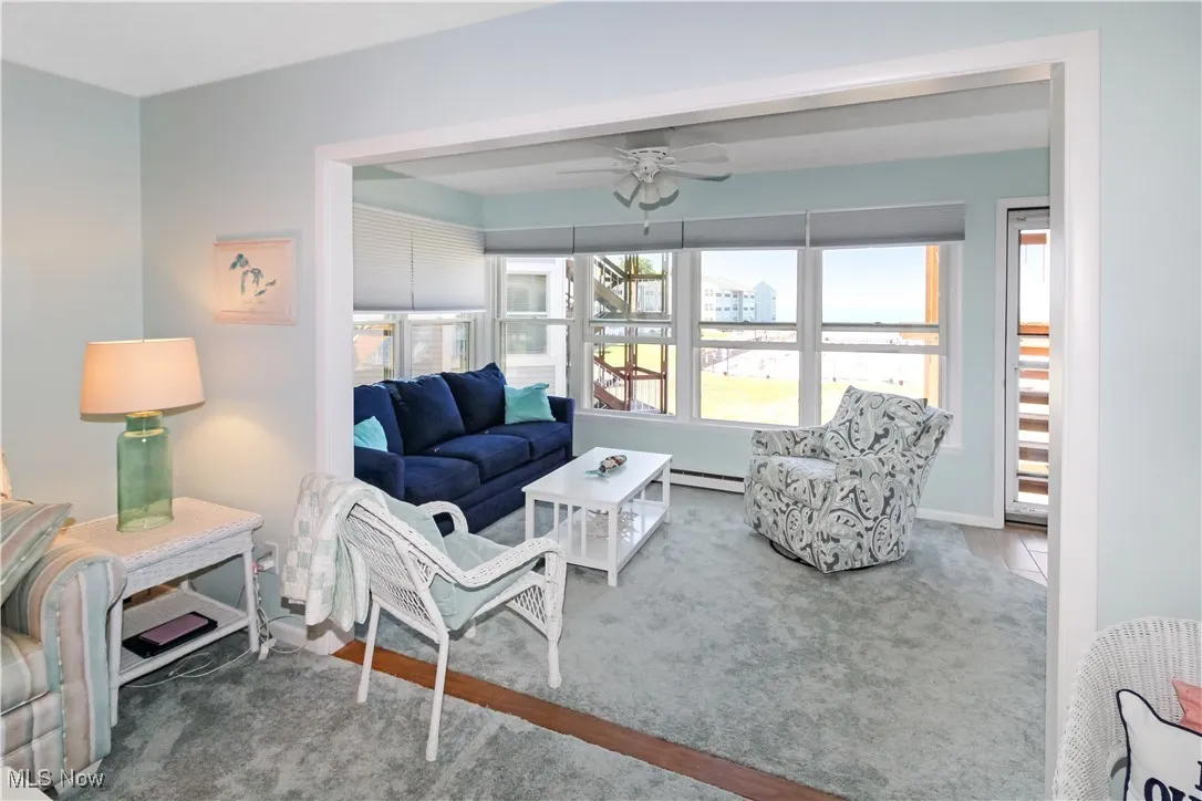Carpeted living room featuring a ceiling fan and a baseboard heating unit