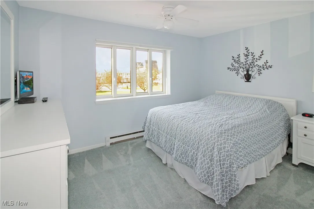 Bedroom featuring light carpet, a baseboard radiator, and ceiling fan