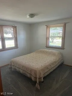 Bedroom with dark colored carpet and baseboards