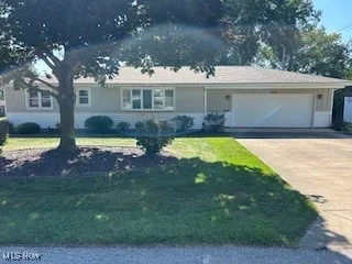 Single story home featuring concrete driveway, a garage, and a front yard