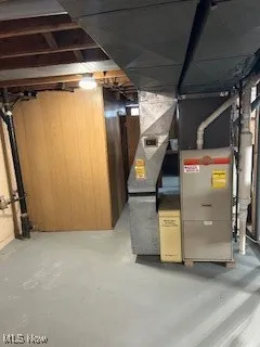 Unfinished basement featuring heating unit and wooden walls