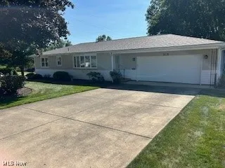 Ranch-style house with an attached garage, concrete driveway, and a front lawn