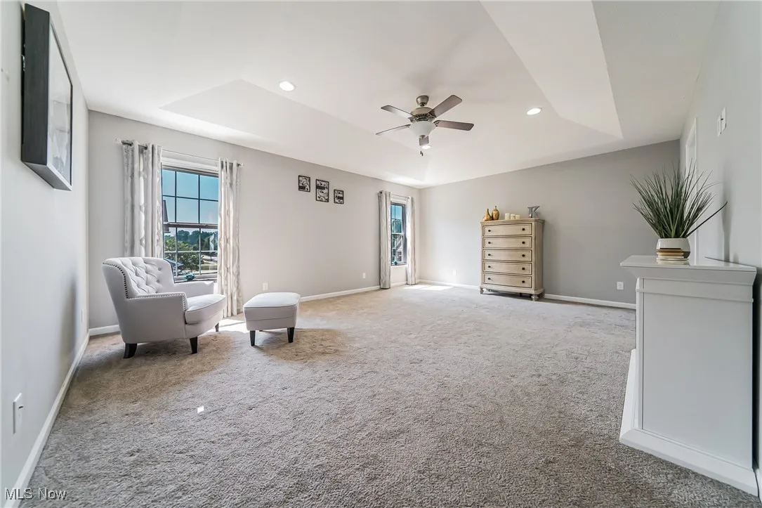 Living area with a tray ceiling, a ceiling fan, carpet, and recessed lighting