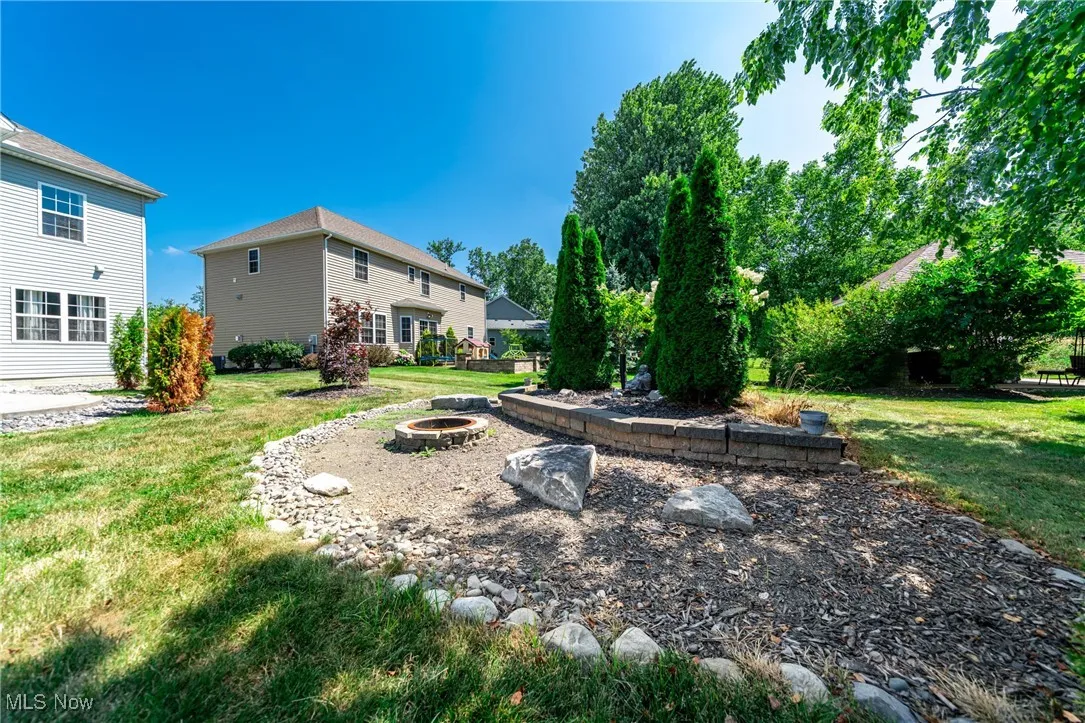 View of grassy yard with an outdoor fire pit