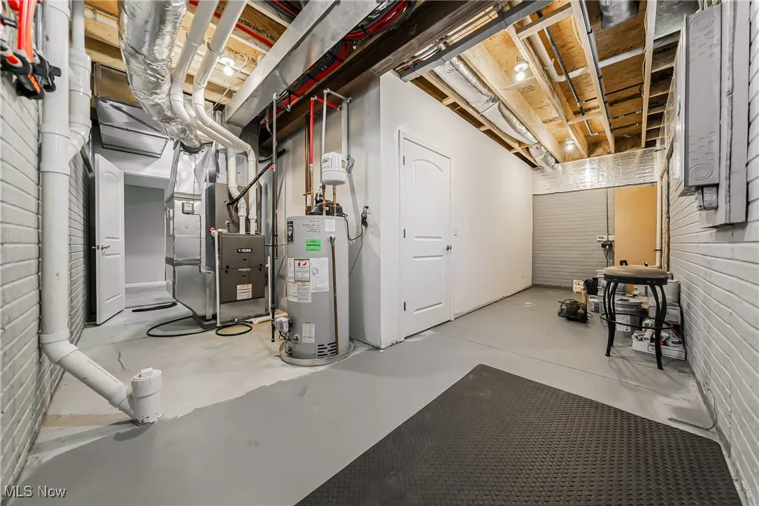 Unfinished below grade area featuring gas water heater and heating unit