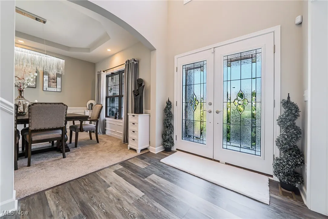 Foyer entrance with french doors, arched walkways, plenty of natural light, dark wood finished floors, and recessed lighting