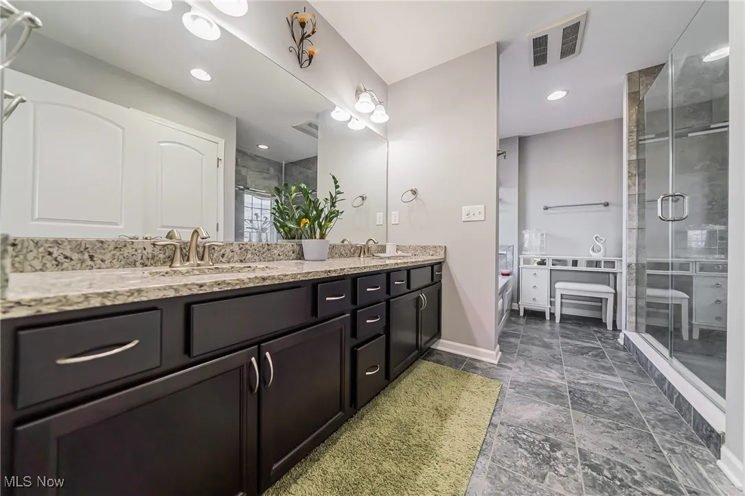 Full bath with double vanity and a stall shower