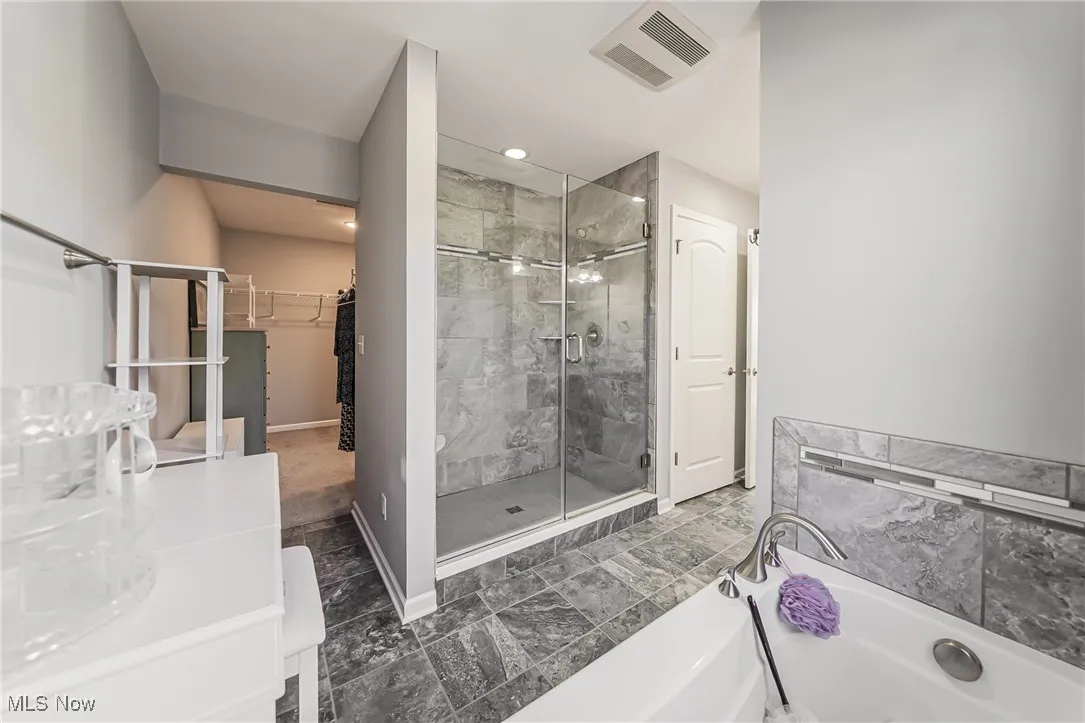 Bathroom featuring a stall shower, a bath, a spacious closet, vanity, and recessed lighting