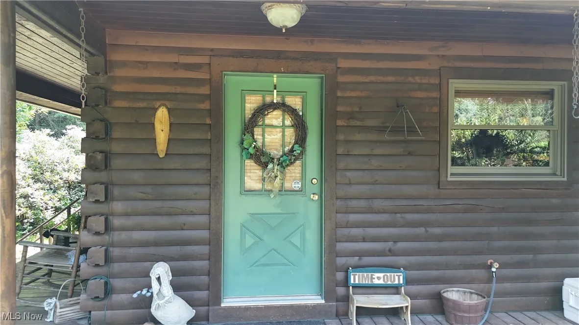 View of exterior entry with faux log siding