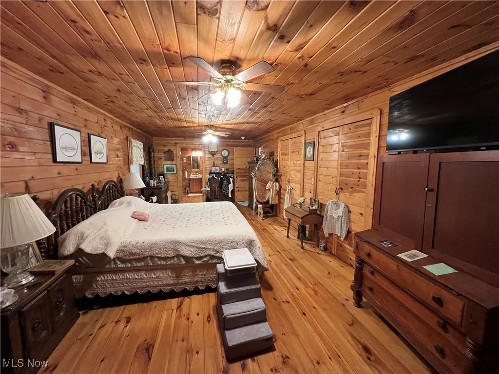 Bedroom featuring wood walls, wooden ceiling, and light wood-style flooring
