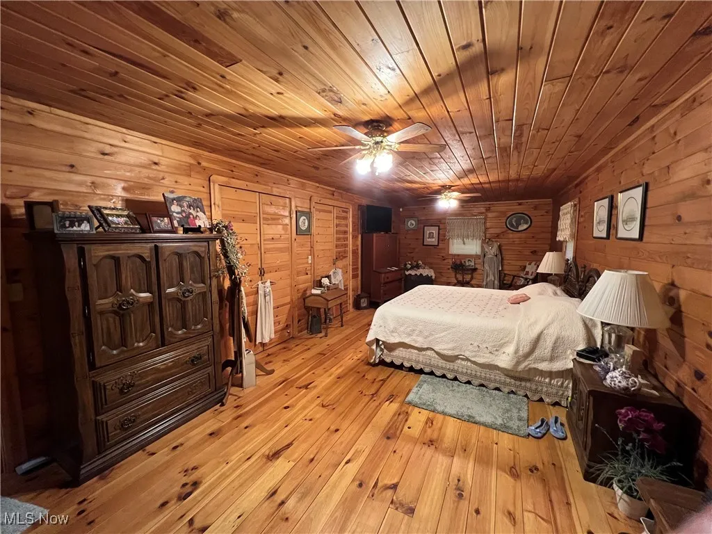 Bedroom with wood ceiling, light wood-style flooring, and wood walls