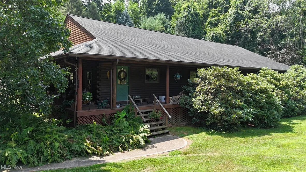 Log cabin featuring a shingled roof, a front lawn, a porch, and log exterior