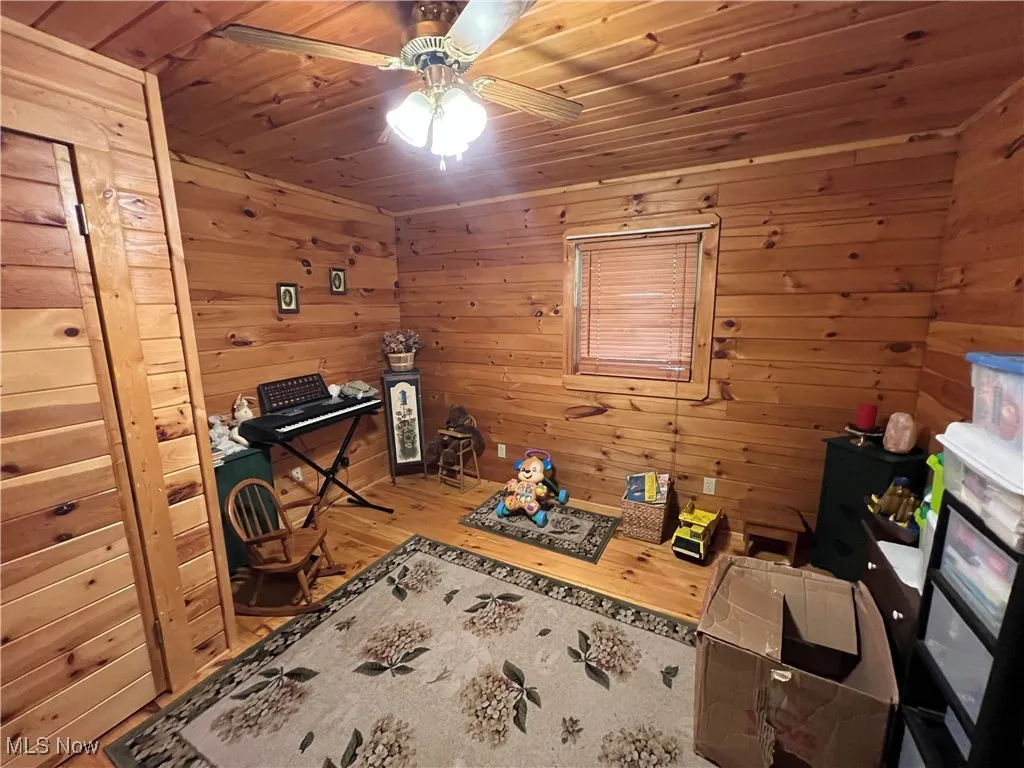 Home office with wood ceiling, wood walls, ceiling fan, and wood finished floors