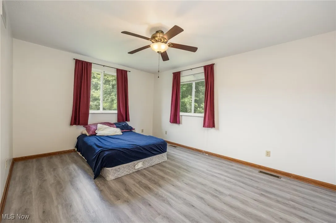 Bedroom featuring multiple windows, wood finished floors, and ceiling fan