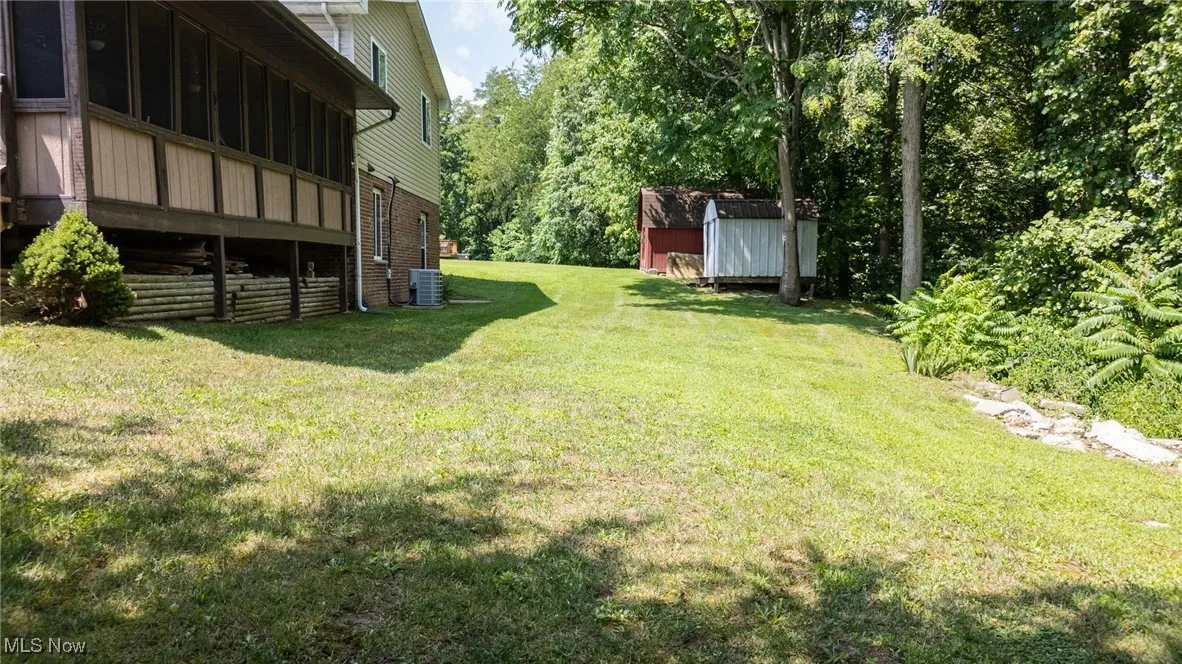 View of green lawn with a shed and a wooden deck