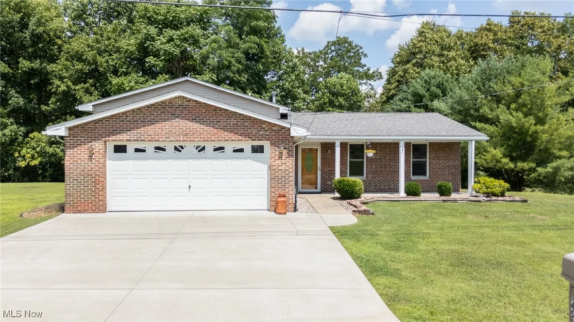 Ranch-style house featuring a garage, driveway, a front yard, and brick siding