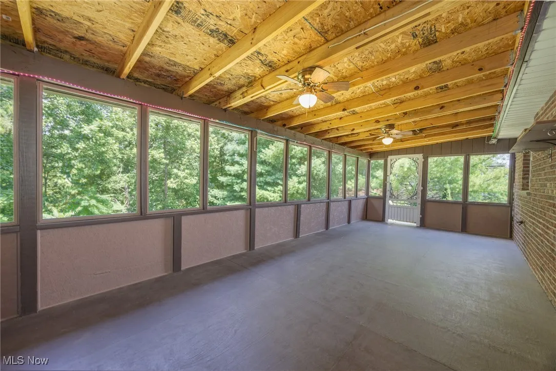 Unfurnished sunroom with ceiling fan and healthy amount of natural light