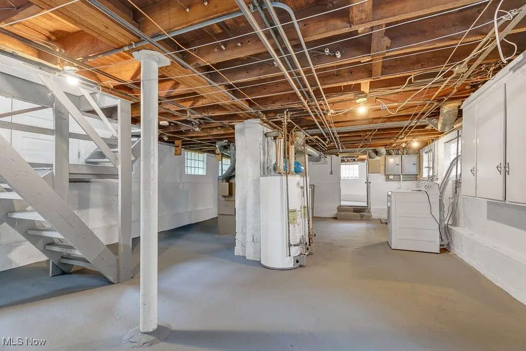 Basement featuring washer and clothes dryer, water heater, stairway, and electric panel