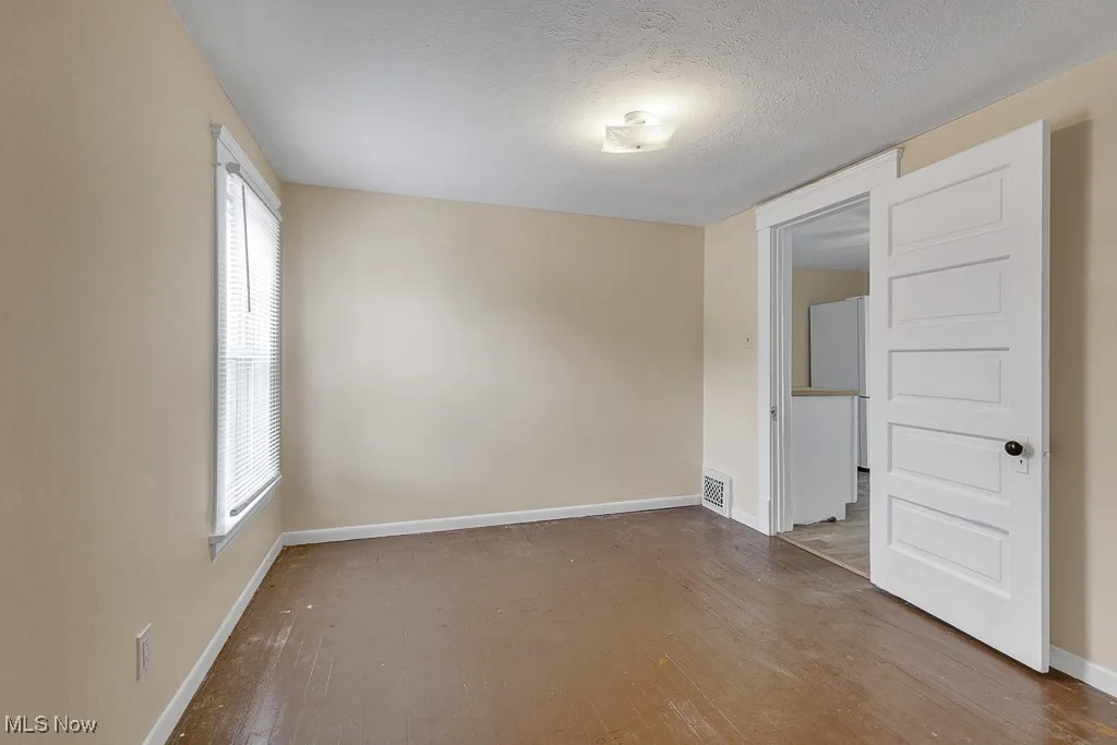 Empty room featuring wood finished floors, plenty of natural light, and a textured ceiling