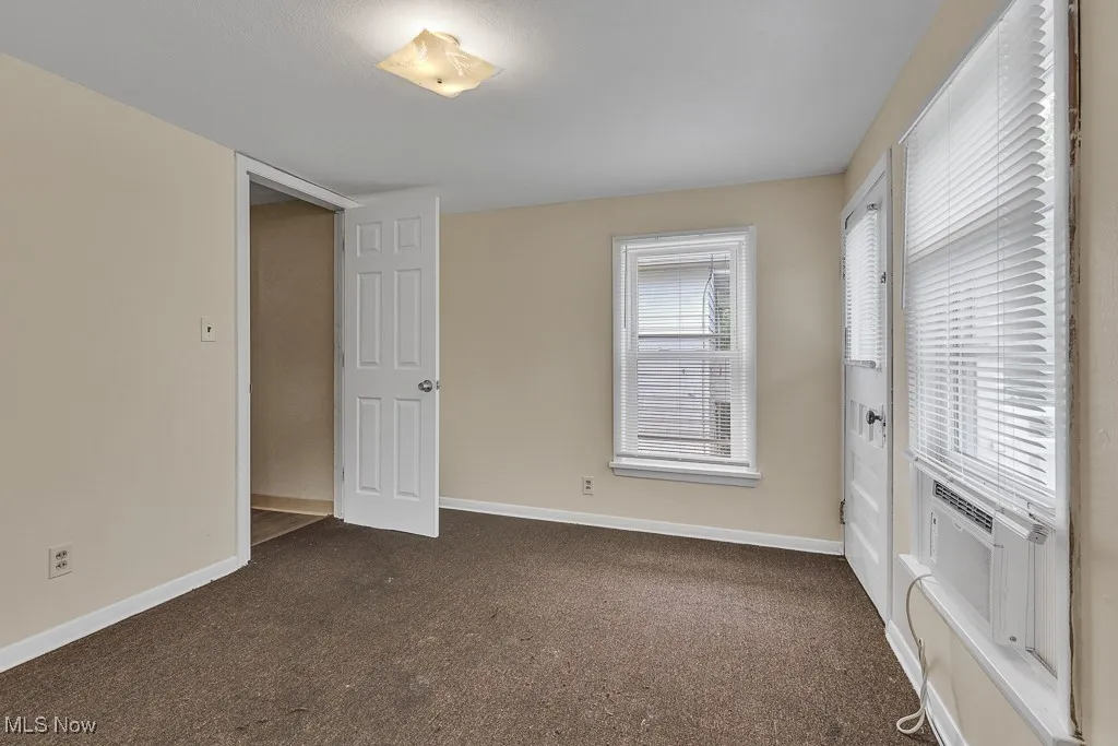 Unfurnished bedroom featuring dark carpet