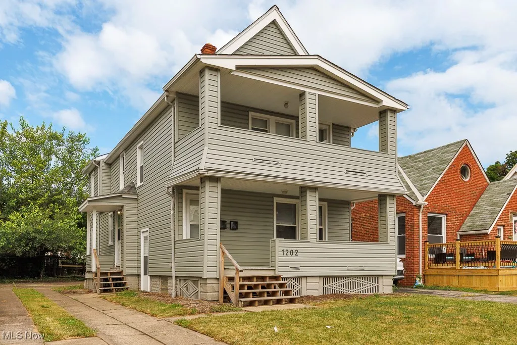 View of front facade featuring a balcony, a chimney, entry steps, and a front lawn