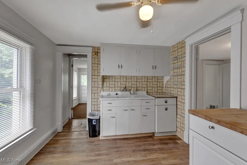 Kitchen with backsplash, light wood-type flooring, white cabinetry, and ceiling fan