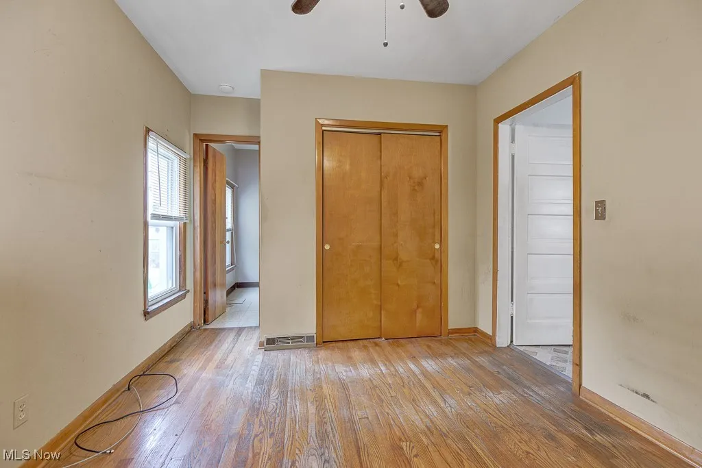 Unfurnished bedroom featuring hardwood / wood-style floors, a closet, and ceiling fan