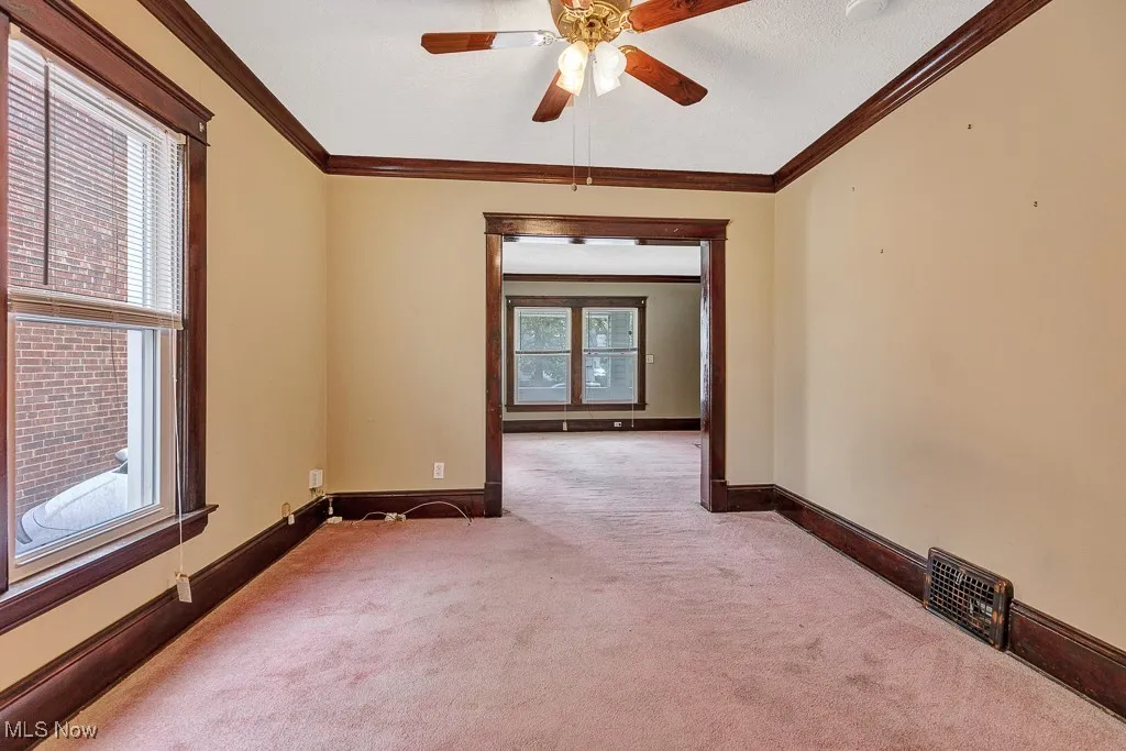 Carpeted spare room with a ceiling fan and ornamental molding