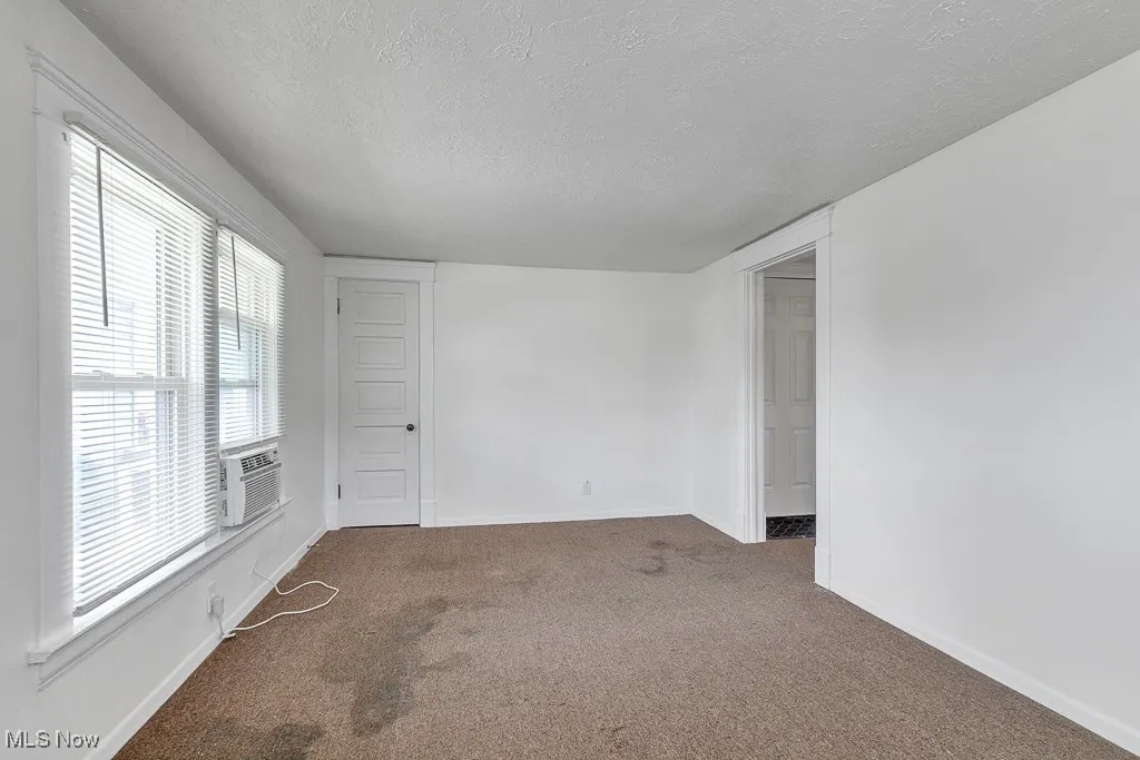 Carpeted empty room featuring a textured ceiling and baseboards