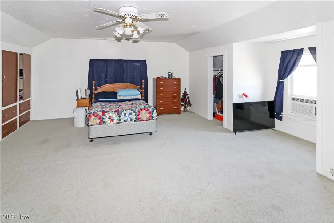 Bedroom with vaulted ceiling, carpet flooring, a ceiling fan, and a closet