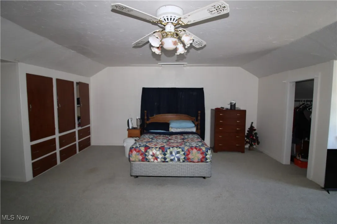 Carpeted bedroom with vaulted ceiling and a ceiling fan