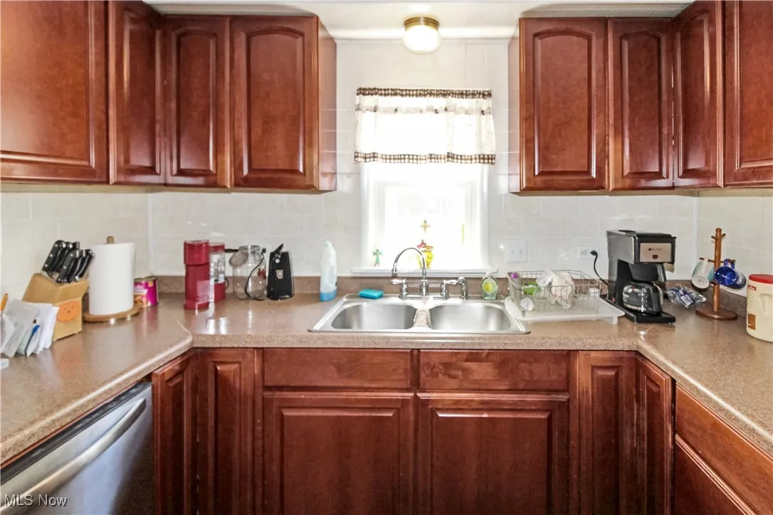Kitchen featuring backsplash, dishwasher, and light countertops